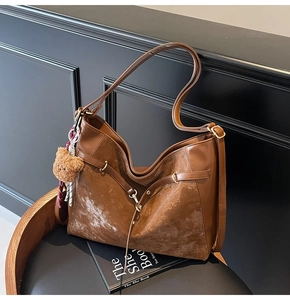 Detail view of brown PU leather shoulder bag with vintage texture and plush bear pendant