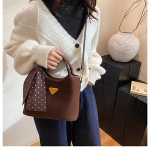 Détail du sac seau mat marron foncé avec foulard à pois et logo triangle en métal