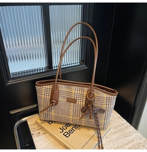 Detailansicht der Vintage-Hahnentritt-Tasche mit braunem Lederbesatz und Metallemblem