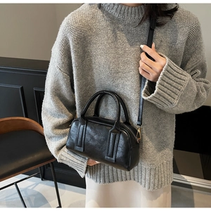 Detail of black pebbled leather pillow bag showing the zipper and embossed logo texture