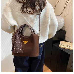 Vue détaillée du sac seau en daim marron foncé avec foulard à pois sur la poignée