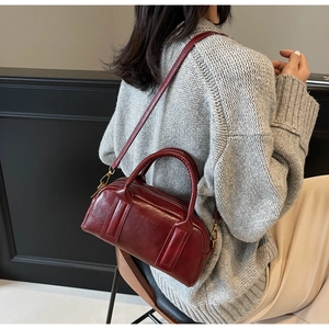 Detail of burgundy matte leather pillow bag with adjustable strap and top handle