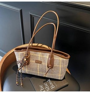 Details der Vintage-Karo-Textur und braunen Lederbesatz an der Retro-Schultertasche
