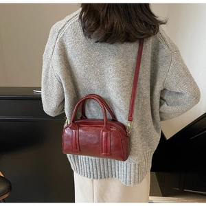 Detail of burgundy Boston bag showing polished leather texture and MOE&KAY brand logo
