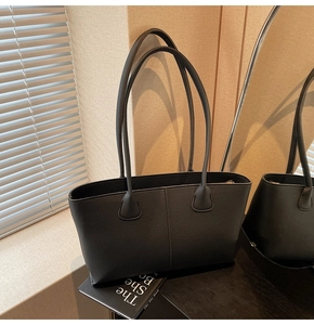 Detail of black pebbled leather tote bag with long handles placed on a window sill