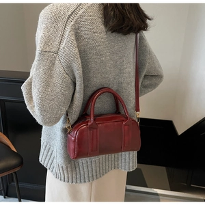 Detail of red vintage leather Boston bag with gold hardware and removable shoulder strap