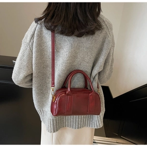 Rear view of a model carrying a deep red vintage boston bag with gold hardware