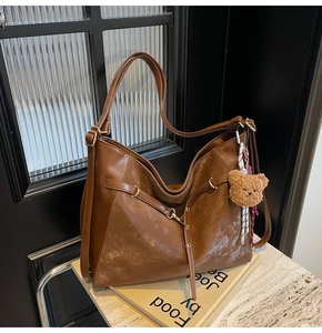 Detail of vintage brown leather tote bag with gold ring buckle and plush bear charm