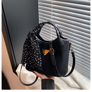 Détail du sac seau en daim noir avec foulard à pois et finitions métalliques