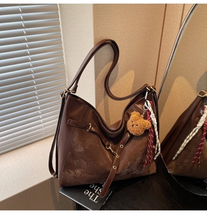 Close-up of brown large tote bag with patchwork leather and cute bear charm decoration