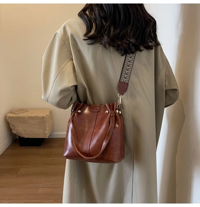 Brown oil wax leather bucket bag with gold studs and vintage woven shoulder strap detail