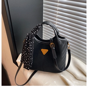 Détail du sac cabas noir avec poignée en foulard à pois et plaque métallique dorée