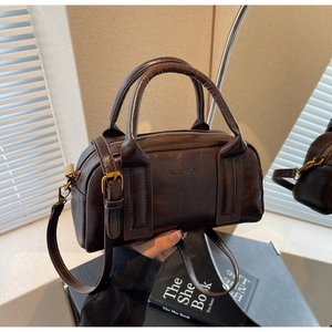 Detail view of a vintage dark brown Boston bag featuring fine leather texture and top handles