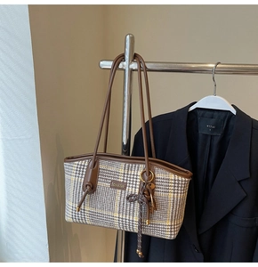 Details einer Vintage-Einkaufstasche mit Hahnentrittmuster und Metall-Namensschild