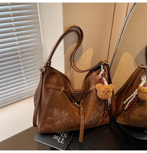 Detail of dark brown tote bag with leather texture and a plush bear keychain charm
