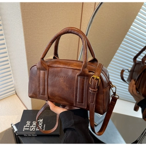 Retro dark brown Boston bag with oil wax texture and vintage bronze hardware in natural light