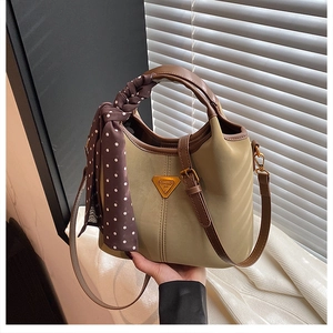 Détail du sac seau vintage mat avec poignées marron et un foulard en soie à pois