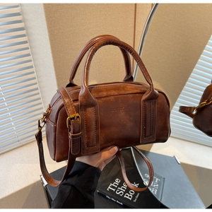 Detail of vintage brown leather pillow bag with double handles and metal hardware buckle