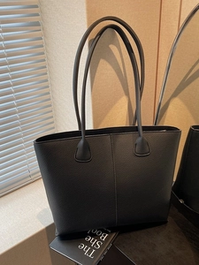 Elegant black lychee texture tote bag with double straps in a modern indoor setting
