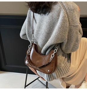 Détail d'un sac hobo en cuir verni marron avec chaîne argentée et bandoulière chic