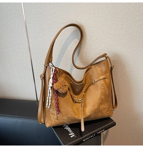 Macro detail of brown vintage PU leather bag with cute plush bear and rope pendant