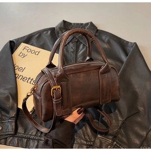 Detailed macro view of dark brown textured leather Boston bag with embossed logo