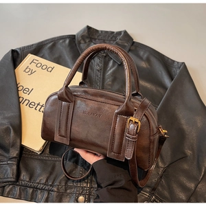 Detail of dark brown vintage Boston bag with MCE&KAY logo and smooth leather texture