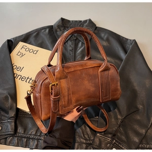 Macro detail of retro brown leather cylinder bag with metallic buckle and handle