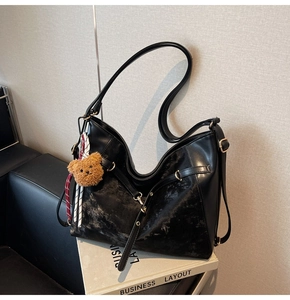 Detailed view of black hobo shoulder bag with matte finish and brown bear pendant