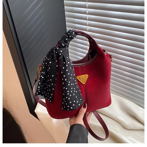 Détail du sac seau bordeaux mat avec poignée en foulard de soie et logo triangle en métal