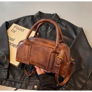 Detail of vintage brown textured leather handbag with bronze hardware and top handles