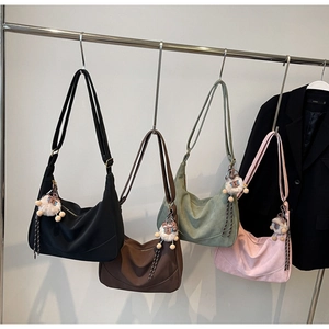 Row of versatile hobo bags in four colors hanging on a rack with plush pendants