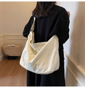 Rückansicht einer Person mit einer beigen Canvas-Hobo-Tasche mit breitem Schultergurt