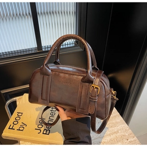 Detail of dark brown vintage Boston bag with gold metal buckle and leather texture