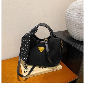 Détail du sac cabas noir mat avec logo triangle jaune et poignée en foulard à pois
