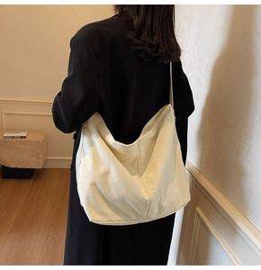 Detailansicht einer übergroßen beigen Canvas-Hobo-Tasche kombiniert mit einem Wollmantel