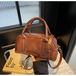 Close-up of the vintage brown leather Boston bag with embossed logo and metal hardware
