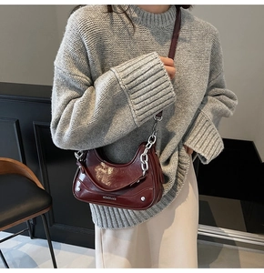 Détail d'un sac à bandoulière en cuir verni rouge foncé avec chaîne et texture gaufrée