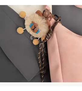 Close-up of a khaki teddy bear plush keychain with a bell on a pink handbag detail