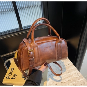 Detail of vintage brown leather boston bag with logo embossing and gold hardware