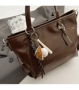 Detail of dark brown wax leather tote bag with branded tag and sports charms