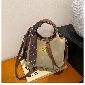 Détail d'un sac seau vintage avec foulard à pois et logo triangulaire élégant