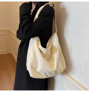 Modellansicht einer stilvollen naturweißen Canvas-Beuteltasche mit breitem Schultergurt
