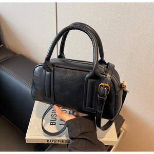 Detail of black glossy Boston bag with embossed logo and bronze gold hardware accents