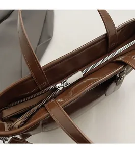 Detailed macro view of smooth silver metal zipper on premium brown oil wax leather tote bag