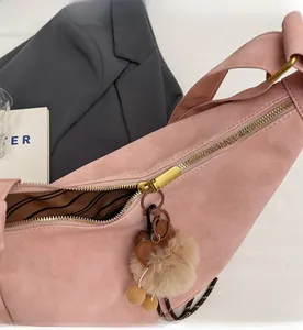 Detailed close-up of smooth gold zipper and soft pink suede material on tote bag