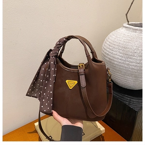Détail d'un sac à main marron vintage avec foulard à pois et logo en métal doré
