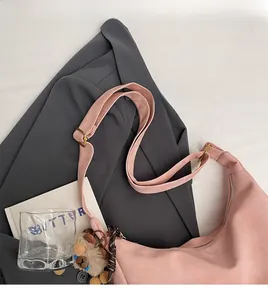 Detail of pink suede tote bag featuring adjustable shoulder strap and plush bear pendant