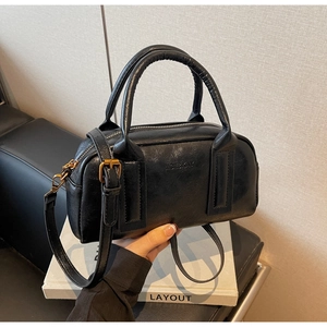 Detail of black PU leather boston bag with fine texture and vintage gold hardware