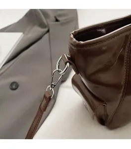 Close-up of silver hardware buckles and detachable strap on dark brown leather tote